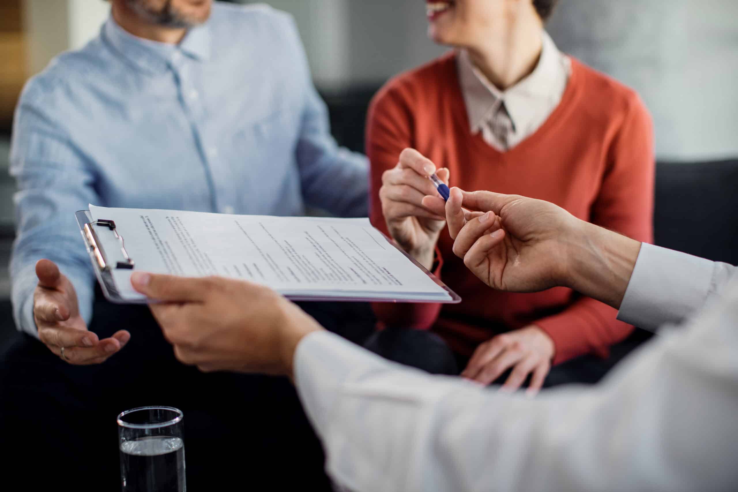 Close-up of unrecognizable couple signing a contract with financ